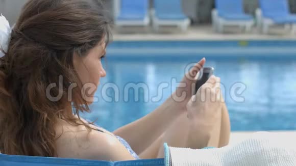 游泳池边的智能手机上浏览互联网的美女视频的预览图