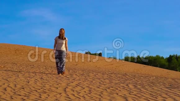 一个穿着亚洲裤子的女孩在红色沙漠的沙滩上慢镜头视频的预览图
