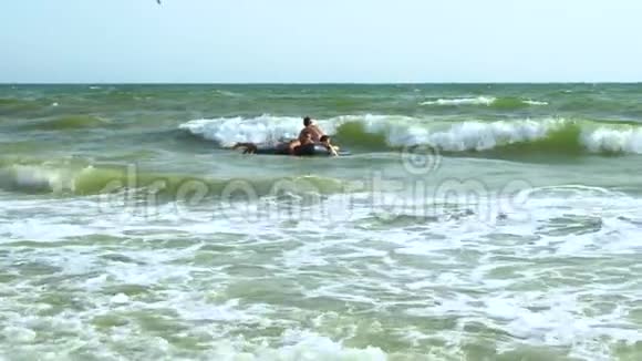 男人在充气床垫上在海里游泳他们在笑床垫在波浪上翻滚慢动作视频的预览图