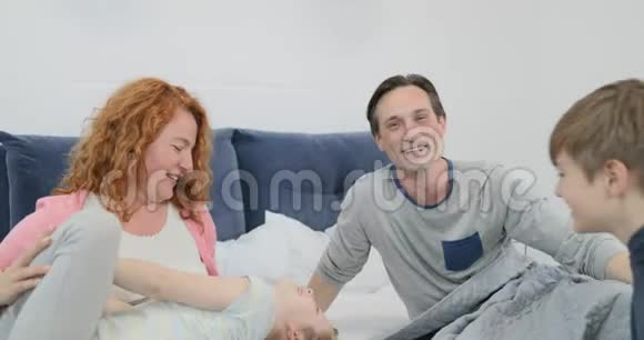 幸福的一家人躺在卧室里坐在床上笑着视频的预览图