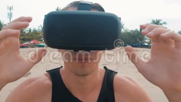 年轻人在海滩上使用虚拟现实眼镜在夏季旅游中使用VR耳机的人获得了经验视频的预览图