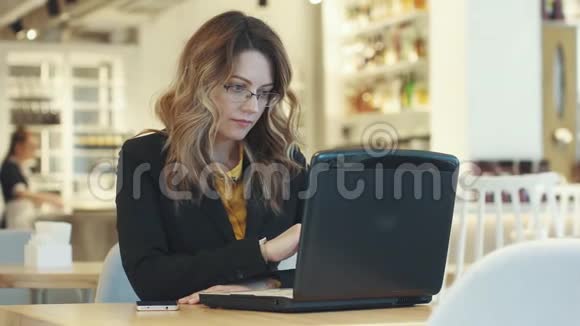 穿着商务服的年轻女人坐在咖啡馆里用笔记本电脑工作非正式工作环境视频的预览图