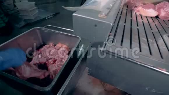 一个人正从一个容器里取出一块块肉把它们放到金属皮带上视频的预览图