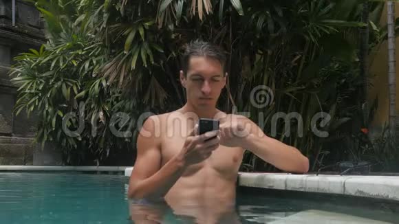 年轻人在游泳池里打电话瀑布智能手机在水里可怜的人在游泳池里丢了一部智能手机视频的预览图