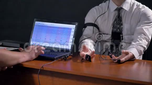测谎仪计算机屏幕旁边的操作员和受试者手视频的预览图