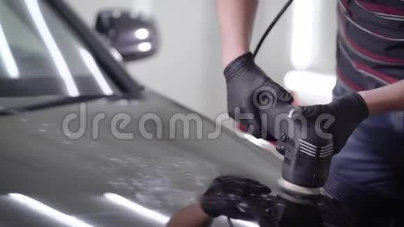 近距离拍摄一名男子打蜡黑色汽车引擎盖使用特殊机器视频的预览图