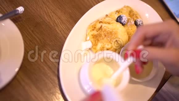 女人在咖啡馆里吃甜点和喝咖啡特写女人把酸奶油放在炸奶酪甜点里美丽美丽视频的预览图