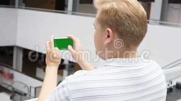 智能手机与绿色屏幕男性手在景观模式下玩游戏易于定制的绿色屏幕看男人视频的预览图