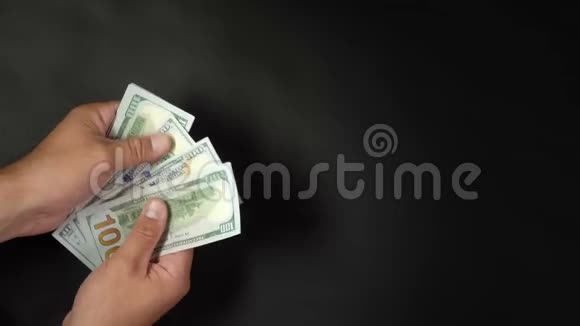 一个人用手在黑色背景上数钱手臂上有4k美元视频的预览图
