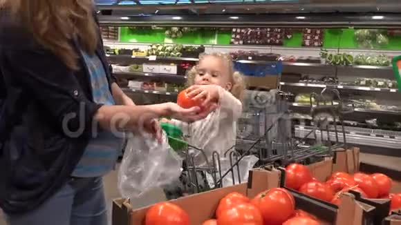 有个可爱孩子的孕妇在超市里摘西红柿水果视频的预览图