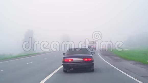 汽车在雾中行驶恶劣的天气和道路上危险的汽车交通雾中的轻型车辆雾状灰色视频的预览图