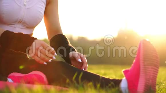 特写的双手在阳光下接过草地上运动鞋的鞋底晨跑前热身美丽美丽视频的预览图