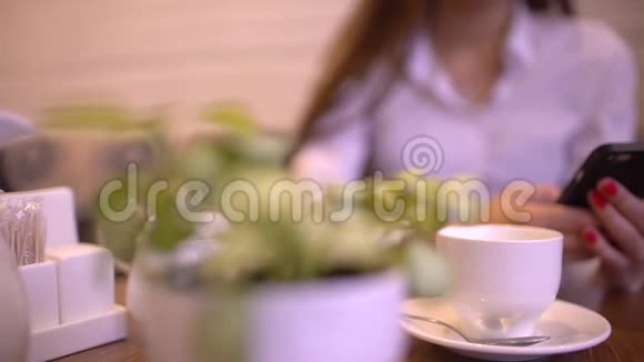 漂亮的女商人在咖啡馆里眼镜在她的智能手机上缓慢地打字视频的预览图