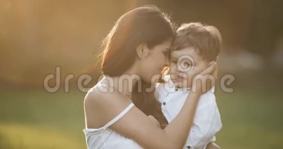 快乐的妈妈抱着儿子在公园里慢动作白色衣服红色史诗视频的预览图