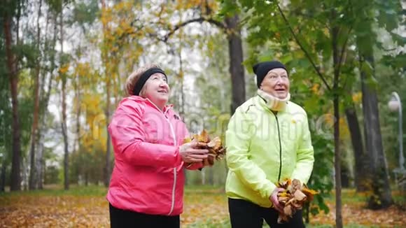 成熟的女人在秋天的公园里向空中扔树叶微笑视频的预览图