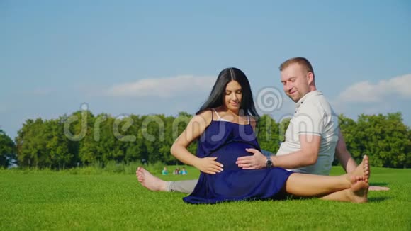 年轻的已婚夫妇期待有个孩子他们一起在草地上的公园里休息视频的预览图