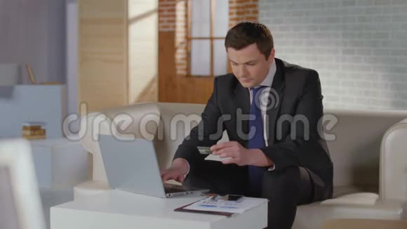 有钱人西装在笔记本电脑上插入信用卡号码视频的预览图