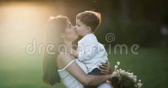 妈妈和她儿子接吻可爱的特写镜头年轻的母亲和她的小儿子在公园里放松和玩耍两者都是视频的预览图
