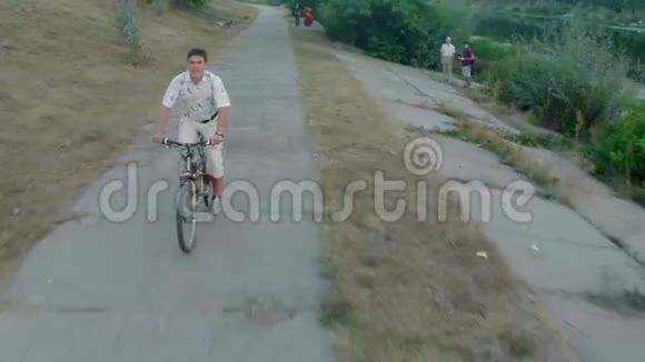 在城市公园骑自行车的微笑年轻人视频的预览图