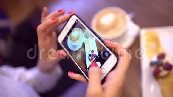 餐馆里的女人用手机相机拍食物把手拿上智能手机拿着食物视频的预览图