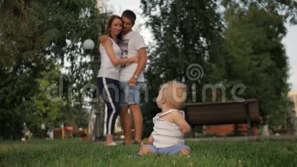 幸福家庭的肖像小男孩坐在公园里父母看着他概念家庭放松视频的预览图