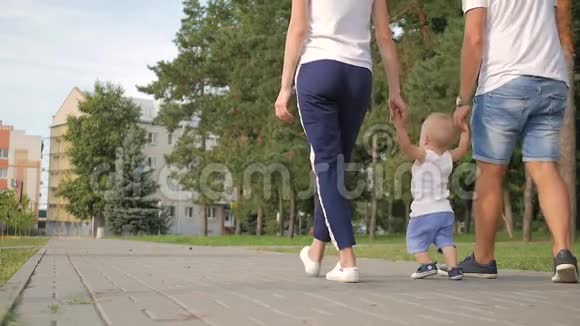 爸爸和妈妈和儿子牵着手在公园里家人在公园散步视频的预览图