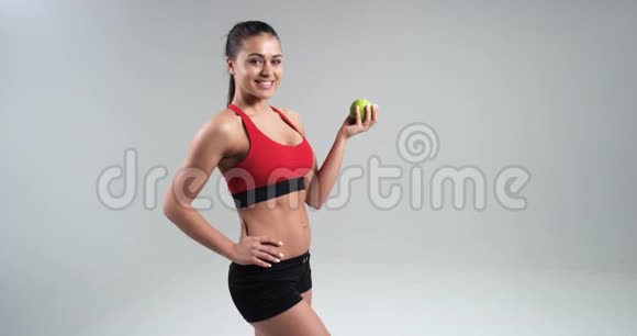 美丽的运动女孩吃绿色苹果运动的概念和健康的饮食4k视频的预览图