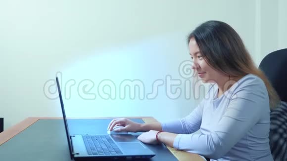 可爱的亚洲女孩在办公室的桌子上使用笔记本电脑视频的预览图