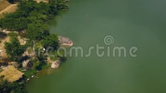 绿色的水和岸上的大石头美丽的湖泊从飞行无人机空中拍摄沿河而行的道路视频的预览图