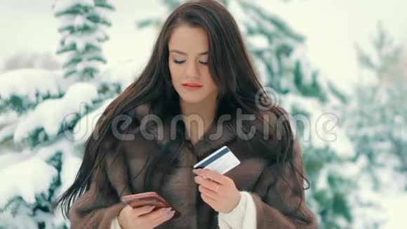 背景圣诞树上有电话和信用卡的女人做购物慢动作视频的预览图