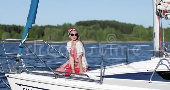 一个穿着连衣裙和太阳镜的漂亮女孩坐在游艇上享受着美丽的风景视频的预览图