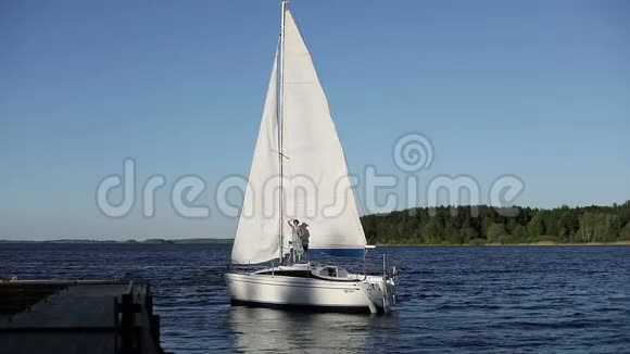 女孩用白色的帆在别致的游艇上挥动她的手视频的预览图
