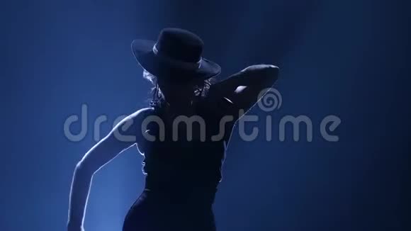 女人戴着帽子跳舞手里拿着蓖麻子跳舞从后面发光黑暗的背景剪影视频的预览图
