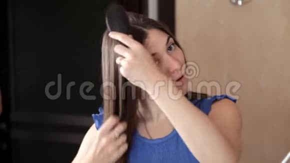 一个年轻女孩站在镜子前梳着长发视频的预览图