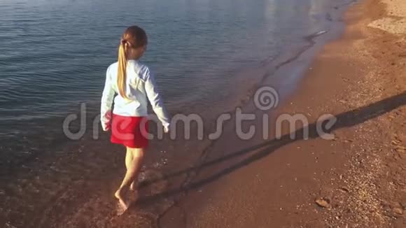 少年女孩白天在海滩上跑步小女孩在海上行走视频的预览图