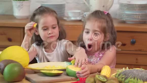 两个可爱的女孩笑着吃了一个多汁的黄色芒果视频的预览图