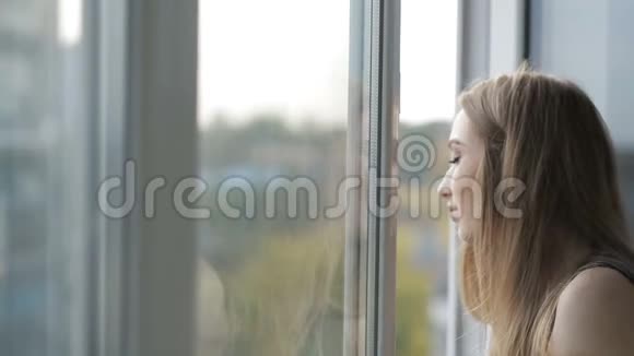 女孩从敞开的窗户呼吸新鲜空气视频的预览图