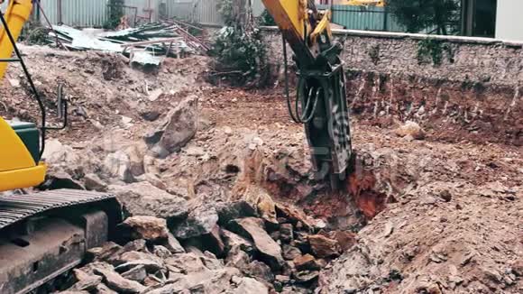 关闭一个重型建筑行业挖掘机在一个建筑工地的石头破碎视频的预览图