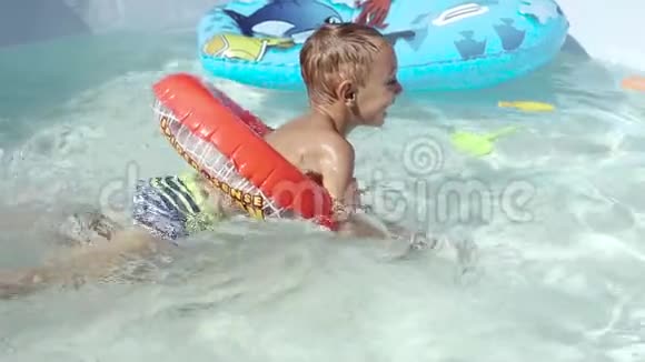 那个男孩漂浮在游泳池里的充气游泳池上视频的预览图