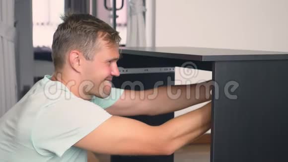 一个年轻人在他家的客厅里组装家具一个男人收集一张电脑桌子视频的预览图