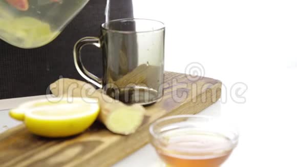 将茶叶倒入带有柠檬和生姜的玻璃透明茶杯中寒冷天气中的暖饮视频的预览图