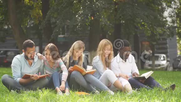 混合种族的学生一起坐在大学校园的绿色草坪上视频的预览图