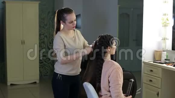 美发师在沙龙为客人做大辫子在美容院编织辫子视频的预览图