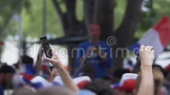 兴高采烈的球迷在智能手机上拍摄视频等待运动队视频的预览图