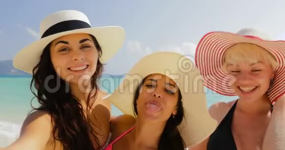 沙滩上的女孩在手机上自拍夏日假日里比基尼和草帽里的快乐女人视频的预览图