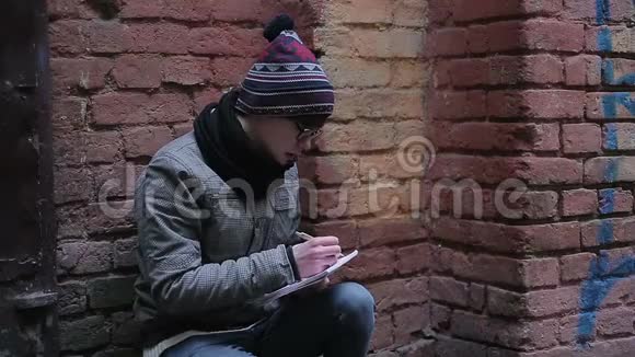 浪漫的年轻人独自坐在荒无人烟的地方用记事本写诗视频的预览图