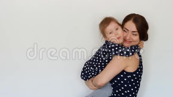 快乐的母亲抱着女儿拥抱亲吻表达母爱抱着孩子的年轻女子视频的预览图