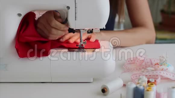 裁缝女手在缝纫机上缝制红布视频的预览图