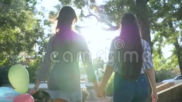 周末快乐长发女朋友手牵着五颜六色的气球在公园里玩得很开心视频的预览图