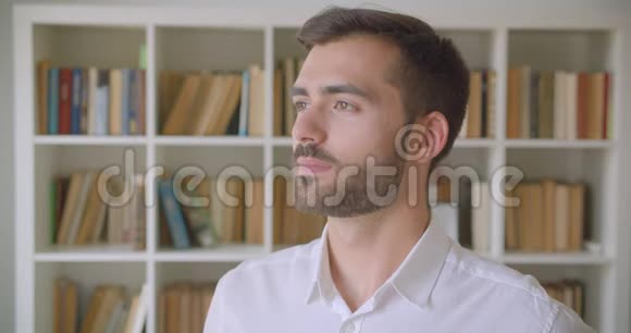 在室内图书馆里一位英俊的白种人成年男子正看着镜头开心地笑着的特写镜头视频的预览图